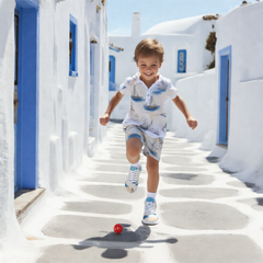 Boy running in the street wearing Boys’ Santorini Travel Sneakers and summer outfit, playing with a red ball.